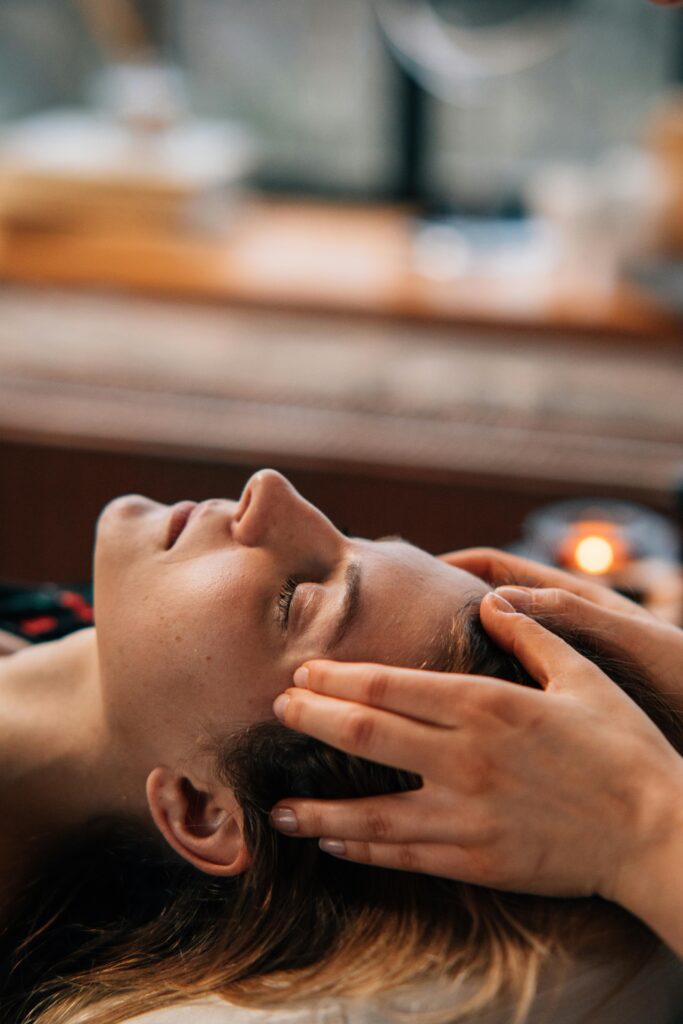 Soins Woman enjoying a relaxing face massage indoors, eyes closed, with hands gently massaging temples.